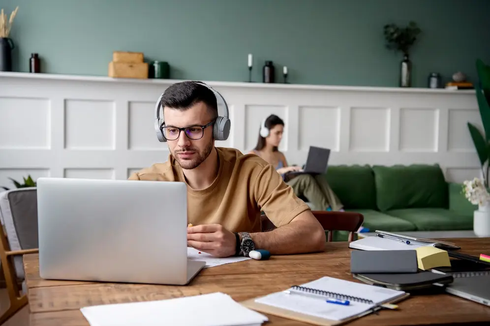un jeune homme suis une formation en ligne à domicile, depuis son ordinateur.