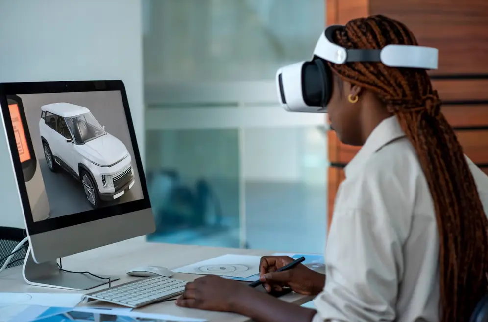 Une femme noire porte un casque de réalité virtuelle tout en travaillant en ligne depuis chez elle. .