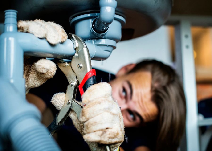 Plombier travaillant sous des sanitaires