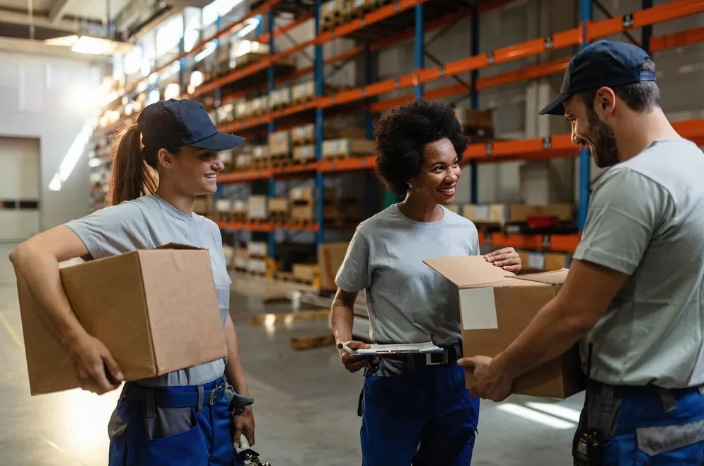 Un logisticien transmet un colis à sa collègue dans un entrepôt de stockage.